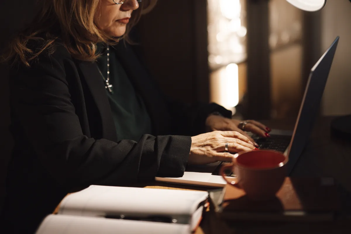 A person typing on a laptop at a home-office desk