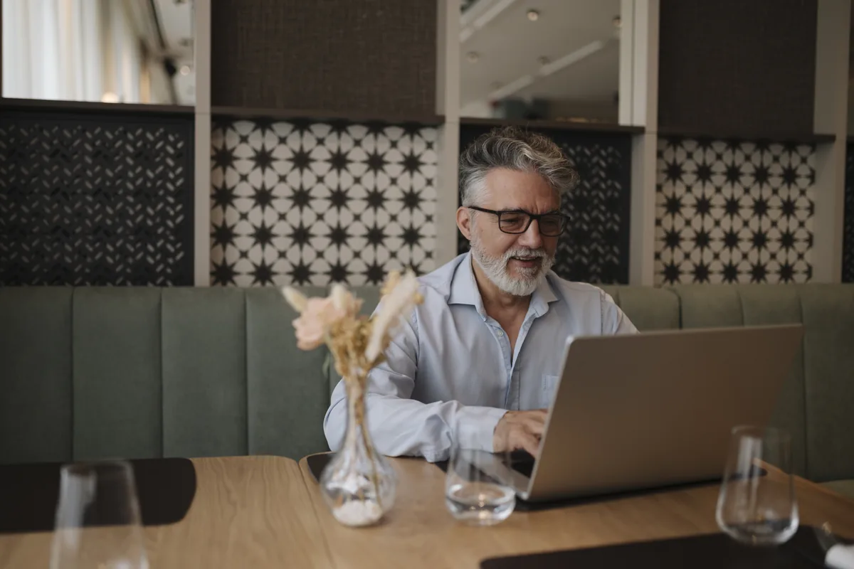 An older man working on a laptop in a cafe