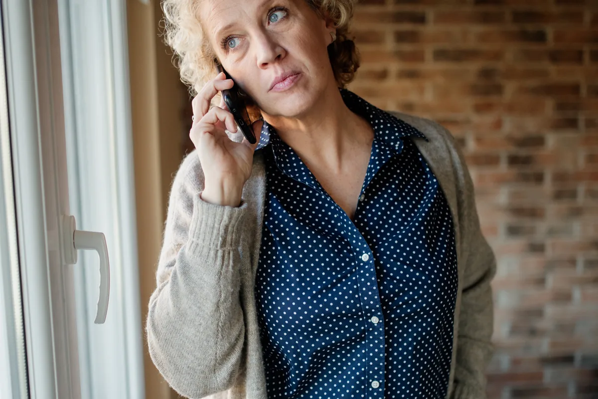 A person talking on the phone while standing by a window