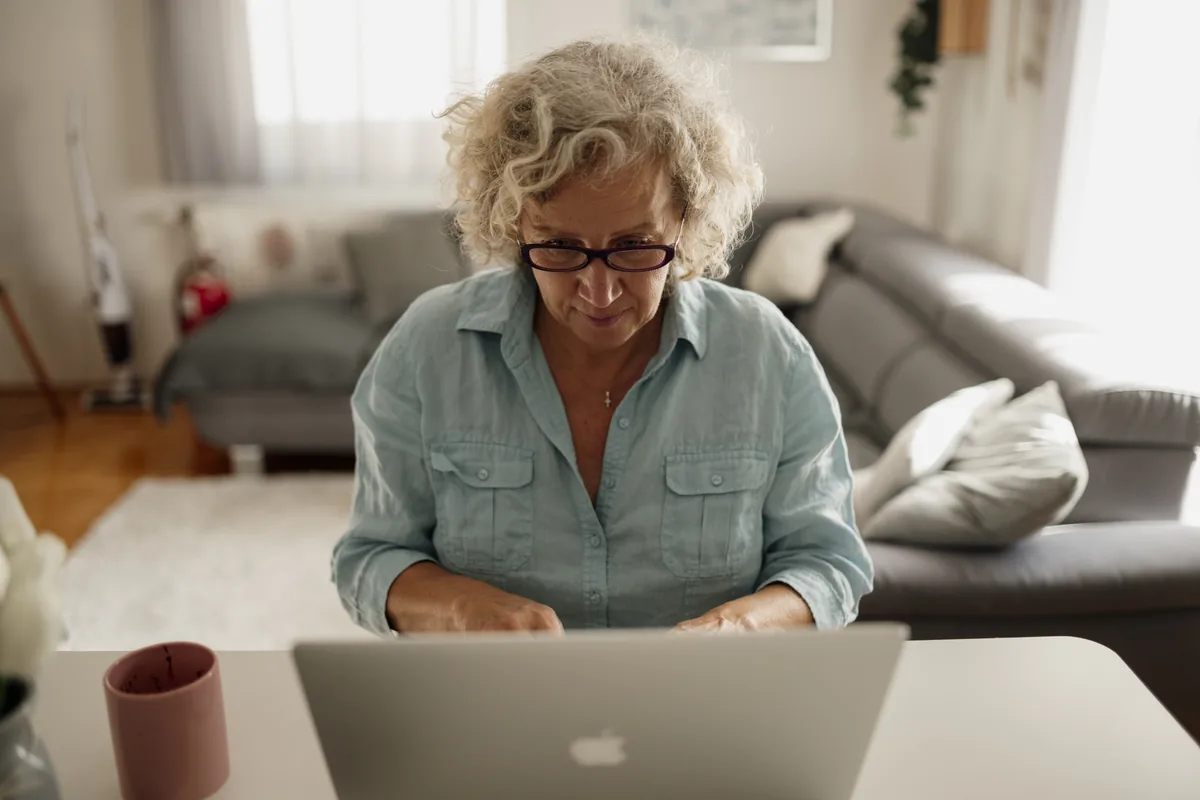 An older adult working on a laptop at home